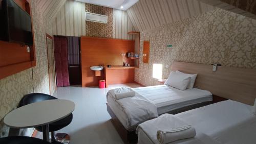 een hotelkamer met 2 bedden, een tafel en een bureau bij Manggasa Hotel in Makale