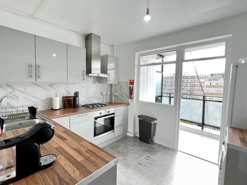 a kitchen with white appliances and a large window at Lovely 3 Bedrooms Flat in London