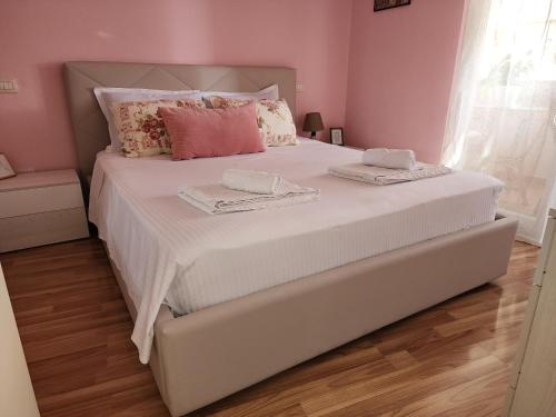 sypialnia z dużym białym łóżkiem i różowymi ścianami w obiekcie Cozy sunlit apartment with scenic balcony view w Tiranie
