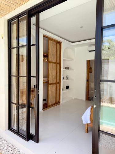 an open glass door in a room with a bedroom at Emma’s Villa in Seminyak