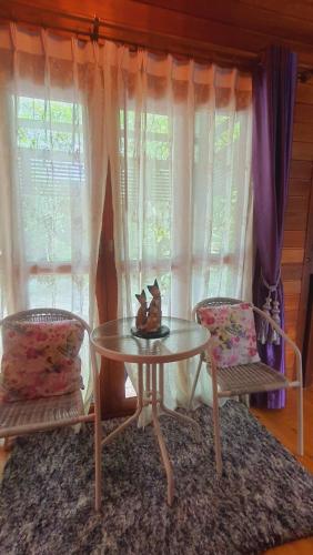 a table and two chairs in a room with a window at Areeya phubeach resort wooden house Coliving Coworking in Ban Chong Phli