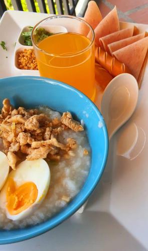 a blue bowl of food with eggs and a glass of orange juice at Areeya phubeach resort wooden house Coliving Coworking in Ban Chong Phli