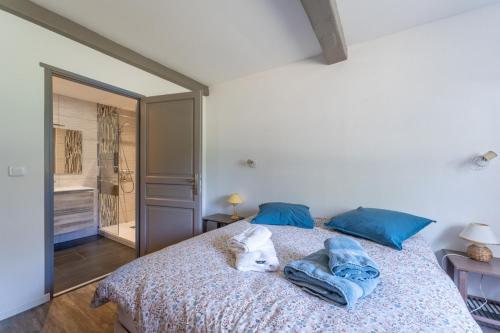 - un chien blanc dormant sur un lit avec des oreillers bleus dans l'établissement Gîte Cascades des Tufs 2 pièces piscine, à La Châtelaine