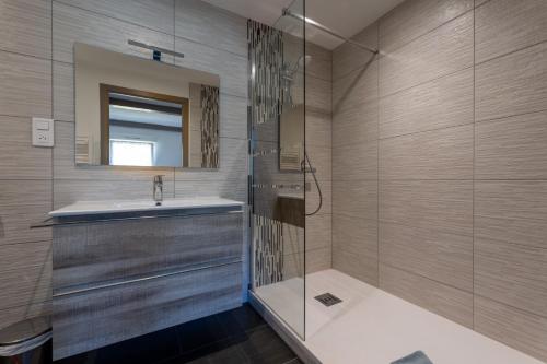 La salle de bains est pourvue d'une douche, d'un lavabo et d'un miroir. dans l'établissement Gîte Cascades des Tufs 2 pièces piscine, à La Châtelaine