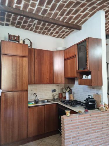 - une cuisine avec des placards en bois et un évier dans l'établissement Il Rifugio sul Colle - Casa vacanze a Campo Felice, à Casamaina