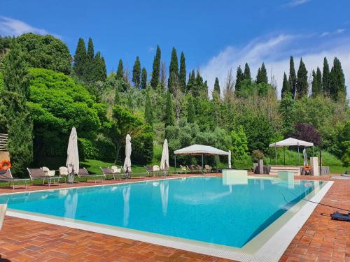 une grande piscine avec des chaises et des parasols dans l'établissement Hotel Antica Tabaccaia Resort, à Terranuova Bracciolini