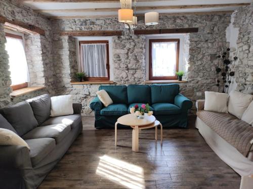 a living room with a blue couch and a table at Casa di Volce - 1801 Stone House in Tolmin