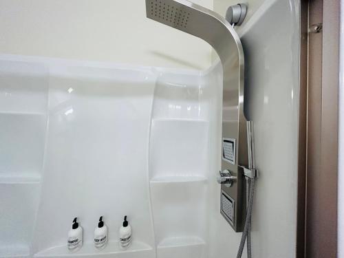 a shower with three black and white bottles in a bathroom at Downtown Digs-View of the City! Stay above local restaurants and nightlife, posh amenities heated toilet seat, oversized rain shower head in glass shower, in-unit laundry, one garage parking spot in Boise