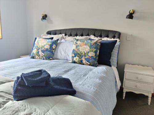 a bed with pillows and a blue towel on it at Large, Comfy, Stylish Apartment in Havelock North
