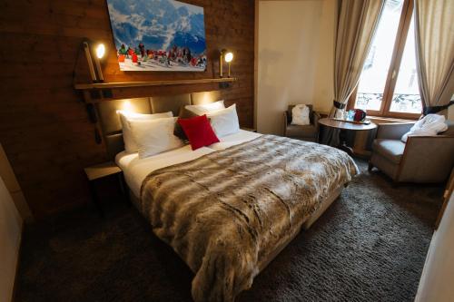 a hotel room with a large bed and a chair at Coeur des Neiges in Saint-Gervais-les-Bains