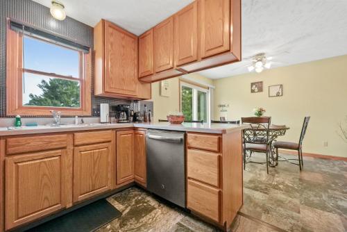 a kitchen with wooden cabinets and a sink and a table at LONG LAKE RETREAT- Hot tub, Pool table, Firepit in Traverse City