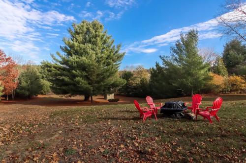 two red chairs and a table in a park at LONG LAKE RETREAT- Hot tub, Pool table, Firepit in Traverse City