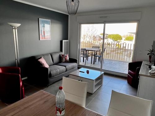 a living room with a couch and a table at T2 neuf + piscine, 5 mn à pied des plages in Sérignan