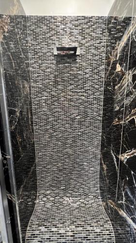 a bathroom with a shower with a black tiled floor at Suites Matteotti 57 in Civitavecchia