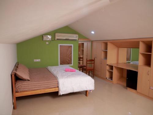 um quarto com uma cama e uma parede verde em Ritu Homestay (The Second Wind) em Trivandrum