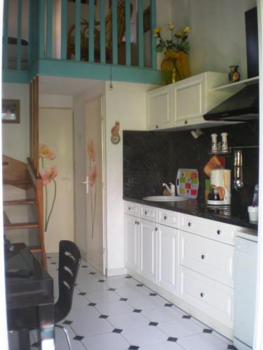 une cuisine avec des armoires blanches et un comptoir noir dans l'établissement Maison de vacances Résidence Agdabella, au Cap d'Agde