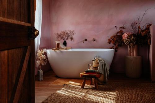 baño con bañera blanca en una pared rosa en Old World Charm - Simplistic Luxury Cottage, en Ross