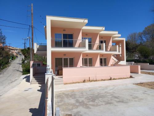 a pink house with a fence in front of it at AVRA-2 Apartments Potamos CORFU in Potamós