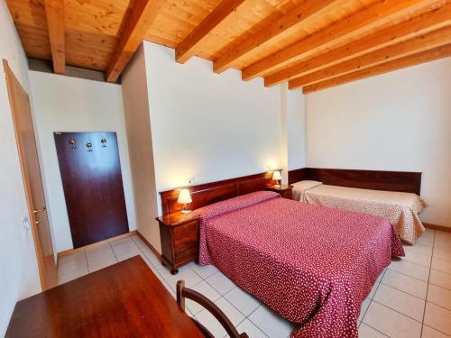 a bedroom with two beds and a wooden ceiling at Agriturismo Ceolara in Sommacampagna