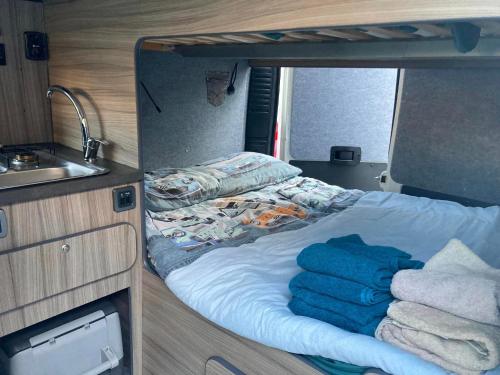 Una cama pequeña en una caravana con toallas. en Campervan and Motorhome Hire Isle of Man, en Kirk Braddon