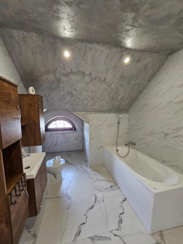 La salle de bains est pourvue d'un lavabo, d'une baignoire et de toilettes. dans l'établissement Vila Kalibu, à Piatra Neamţ
