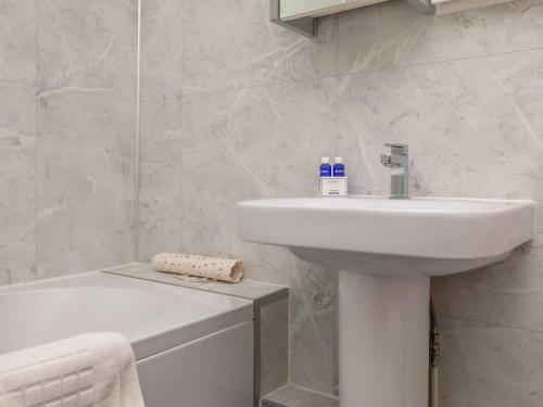 a white bathroom with a sink and a bath tub at Watch Cottage - Uk6729 in Lydstep