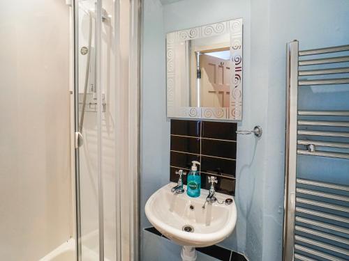 uma casa de banho com um lavatório e um chuveiro com um espelho. em The Rennie Mackintosh Retreat em Comrie