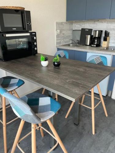 una mesa en una cocina con 2 sillas y microondas en Studio 4 pers proche de la mer, en Camiers