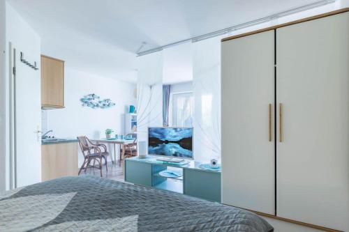 a bedroom with a large white cabinet and a kitchen at FeWo Blåkulle im Haus Seeblick - Wohnung 11 in Hohenkirchen