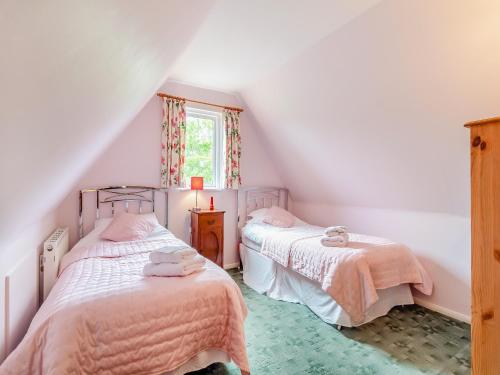 two twin beds in a attic bedroom with a window at Bryanstown Annexe in Woodbridge