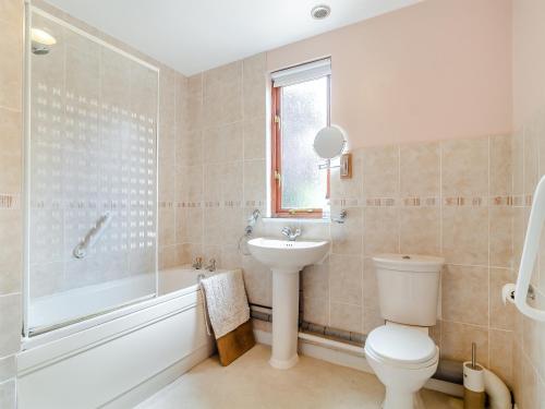 a bathroom with a toilet and a tub and a sink at Bryanstown Annexe in Woodbridge