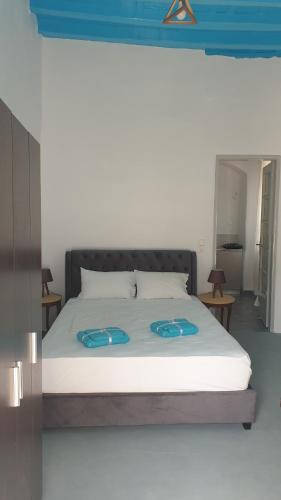 ein Schlafzimmer mit einem Bett mit blauen Hausschuhen darauf in der Unterkunft StathisApart1 in Amorgós