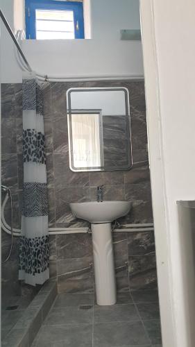 ein Bad mit einem Waschbecken und einem Spiegel in der Unterkunft StathisApart1 in Amorgós