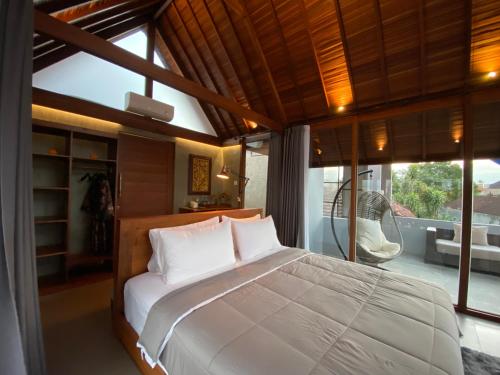 a bedroom with a large bed and a large window at Dewa Hostel in Ubud