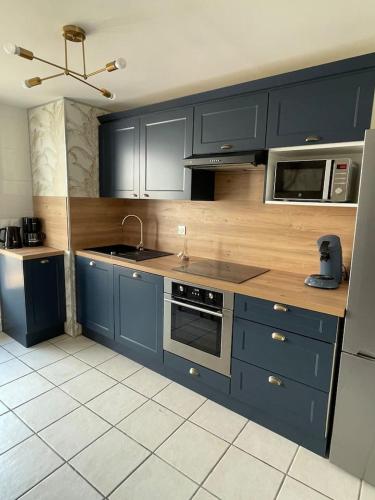 La cuisine est équipée de placards bleus, d'un évier et d'un four micro-ondes. dans l'établissement La Blériotine, à Sangatte