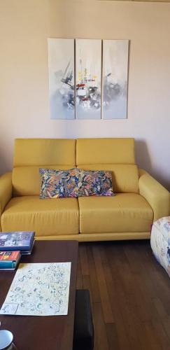 - un canapé jaune dans le salon orné de peintures dans l'établissement La villa des chimères, à Sarlat-la-Canéda