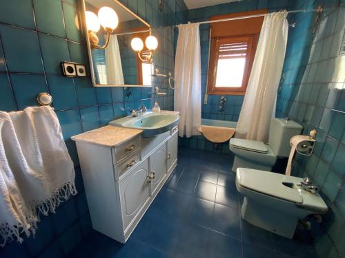 Un baño con azulejos azules, lavabo e inodoro. en Casa Juani, en Ateca