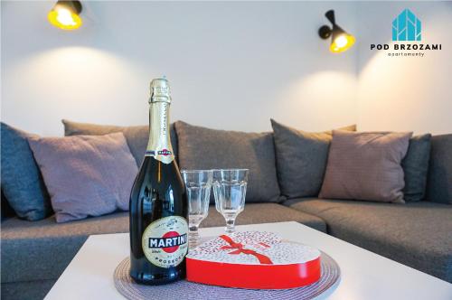 a bottle of wine sitting on a table with two glasses at Pod Brzozami Apartamenty 5 Mórz in Ustronie Morskie