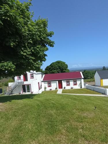 Casa blanca con techo rojo y patio en Tiernan's Luxury Cottages, en Charlestown