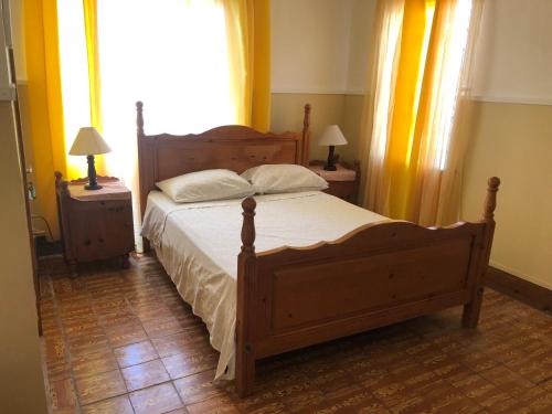 a bedroom with a large wooden bed with two night stands at Nat’s place in Treasure Beach