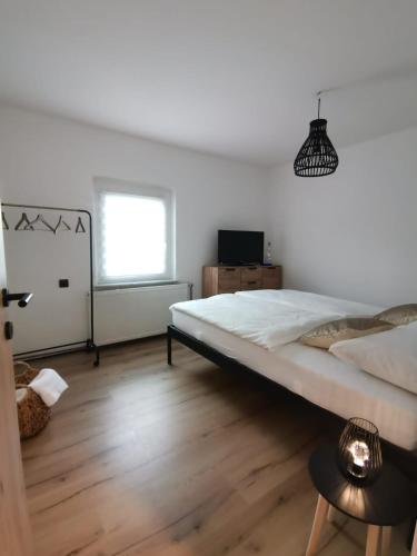 a white bedroom with a large bed and a window at Apartma KORPEC in Ivanjkovci
