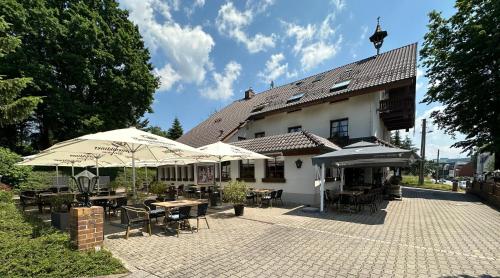 a patio with tables and umbrellas in front of a building at Hotel Almenrausch in Neukirchen
