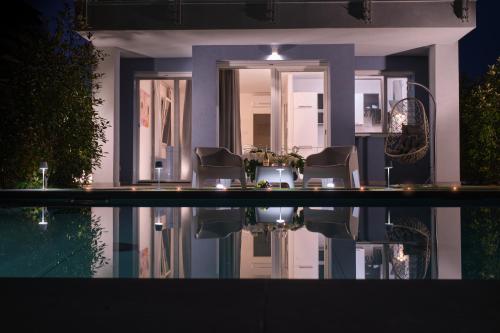 a house with chairs and a swimming pool at night at Villa Karolina Luxury Pool Villa Desenzano del Garda in Desenzano del Garda