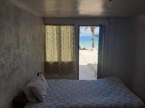 a bedroom with a bed and a view of the beach at Magic's Place Beach Resort in Moalboal