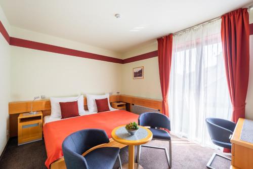 a hotel room with a bed and a table and chairs at Jan Maria Hotel & Restaurant in Ostrava