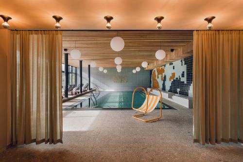 una sala de piscina con una silla y una piscina en The Comodo Bad Gastein, a Member of Design Hotels, en Bad Gastein