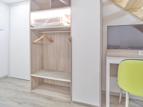 a room with a closet with a tv and a green chair at Hotel Medusa in Finale Ligure