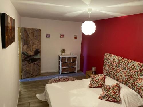 una camera da letto con un letto bianco e una parete rossa di Gîte du Voyageur de la Maison Blanche 4p a Saint-Yzans-de-Médoc