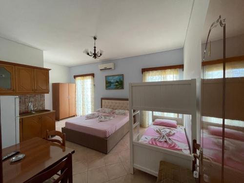 a bedroom with two beds and a desk and a kitchen at Garden Villa Veli in Ksamil