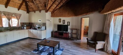 a living room with a table and a kitchen at Mothopo Game Lodge in Modimolle